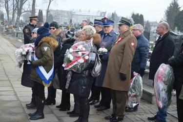 Złożenie kwiat&oacute;w przed pomnikiem na cmantarzu parafialnym