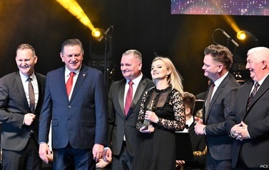 grupa os&oacute;b stoi na scenie 