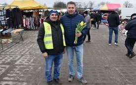Pracownict Referatu Obsługi Targowisk pomagający w wręczaniu tulipan&oacute;w w imieniu Burmistrza