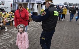 Strażnik Miejski w imieniu Burmistrza wręcza kwiatki 