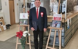 Burmistrz w urzędzie na tle zdjęć z ubiegłorocznych uroczystości