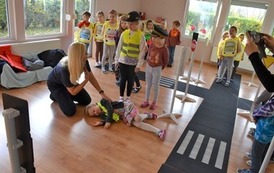 Strażniczka Miejska tlumaczy grupie dzieci jak nalezy postąpić gdy znajdzie nieprzytomną osobę