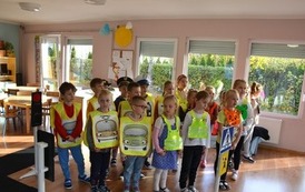 Grupa dzieci ubrana w kamizelki odblaskowe stoją w sali przedszkola 
