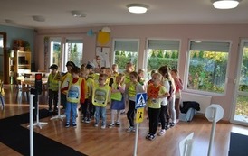 Grupa dzieci stojąca w pomieszczeniu przy sztucznej infrastrukturze drogowej 