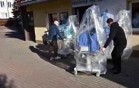 dw&oacute;ch pan&oacute;w transportuje aparat do dializ do budynku Stowarzyszenia Idziemy na spacer 
