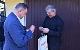 Burmistrz Płońska i ksiądz Wiaczesławowi Doroszowi ubrani w garnitur wymieniają sie wizyt&oacute;wkami 