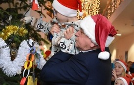 Burmistrz Płońska i dzieci zawieszają bombki na choinkę