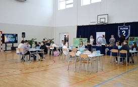 uczestnicy konkursu siedzą w grupach przy stołach 