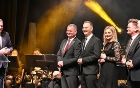 grupa os&oacute;b stoi na scenie 