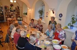 Seniorzy przygotowujący wsp&oacute;lniy posiłek na urodziny Klubu Senior+